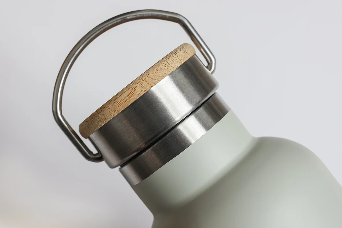 Stainless steel bottle lid with bamboo top and metal handle detail