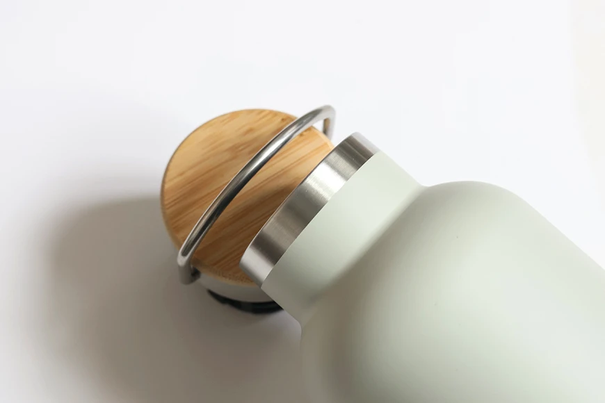 Stainless steel bottle lid with bamboo top and metal handle detail